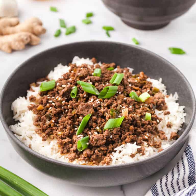 Korean ground beef in a bowl over rice and topped with green onions.