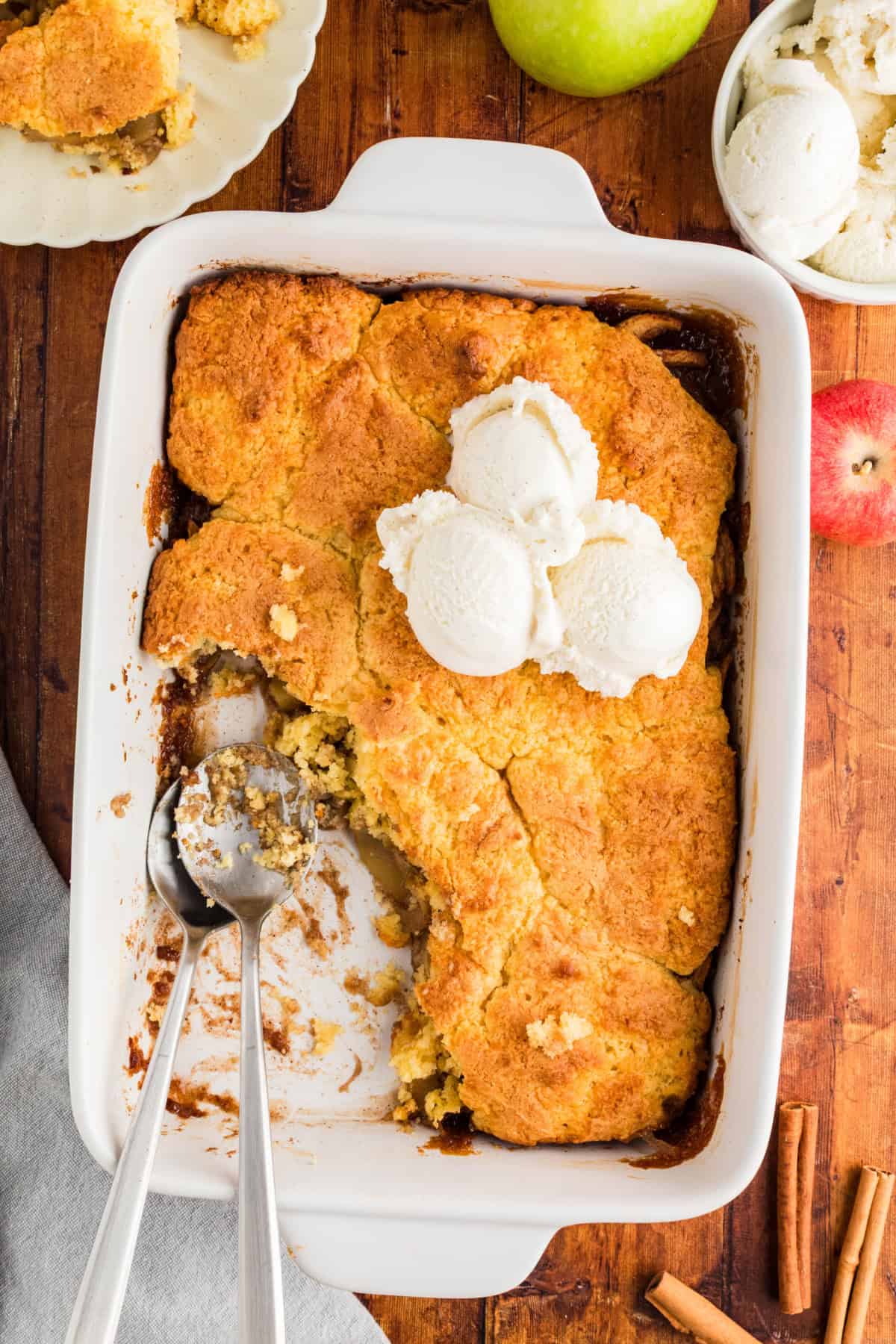 Overhead view of a baking pan of apple cobbler made with cake mix, with ice cream on top.