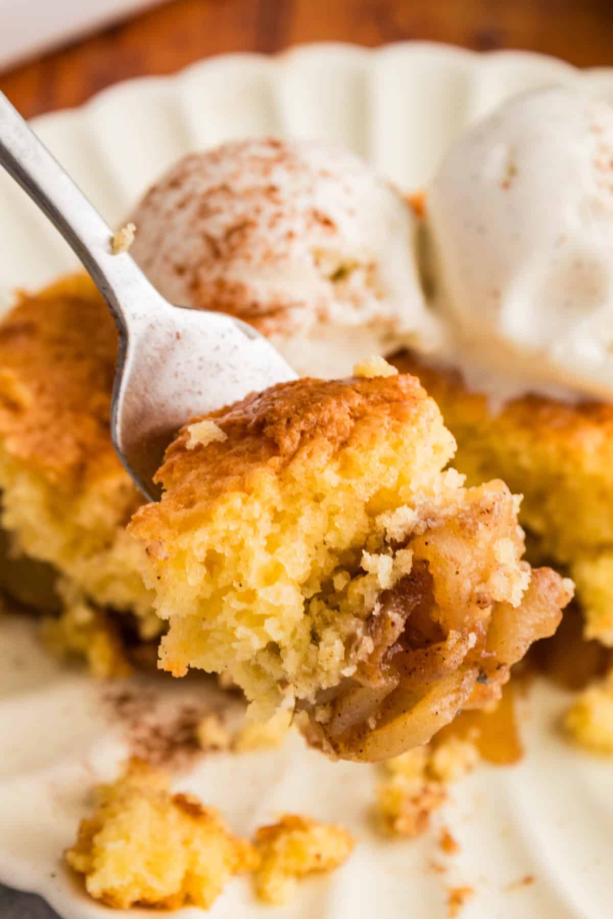 A closeup of a fork with cake mix apple cobbler on it.