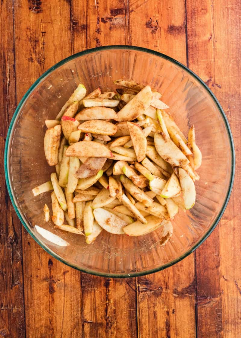 sliced apples and spices in a glass bowl.