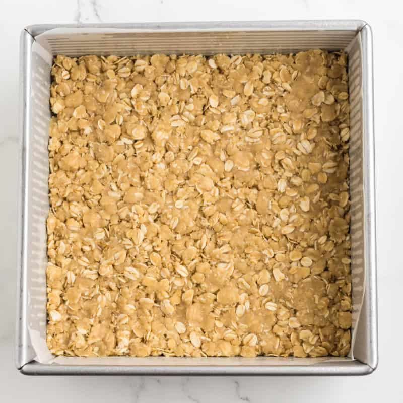 An oat crust in a baking pan for pineapple rhubarb dream bars.