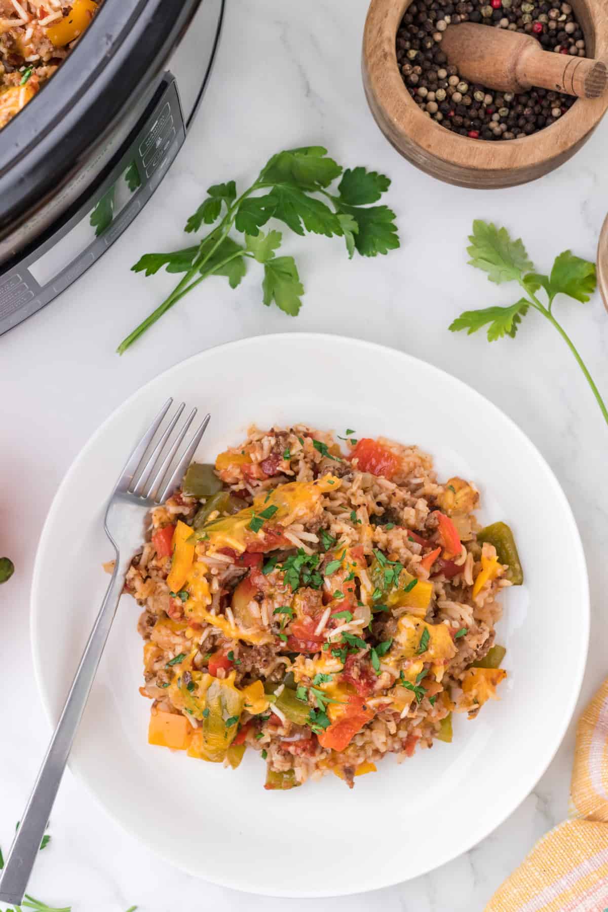 Slow Cooker Stuffed Pepper Casserole on a white round plate beside a crockpot.