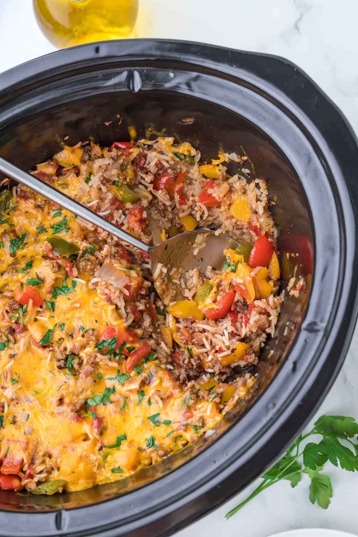 Cooked Slow Cooker Stuffed Pepper Casserole in a black crockpot with a ladle.